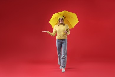 Photo of Woman with yellow umbrella on red background