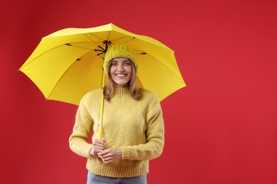 Woman with yellow umbrella on red background, space for text