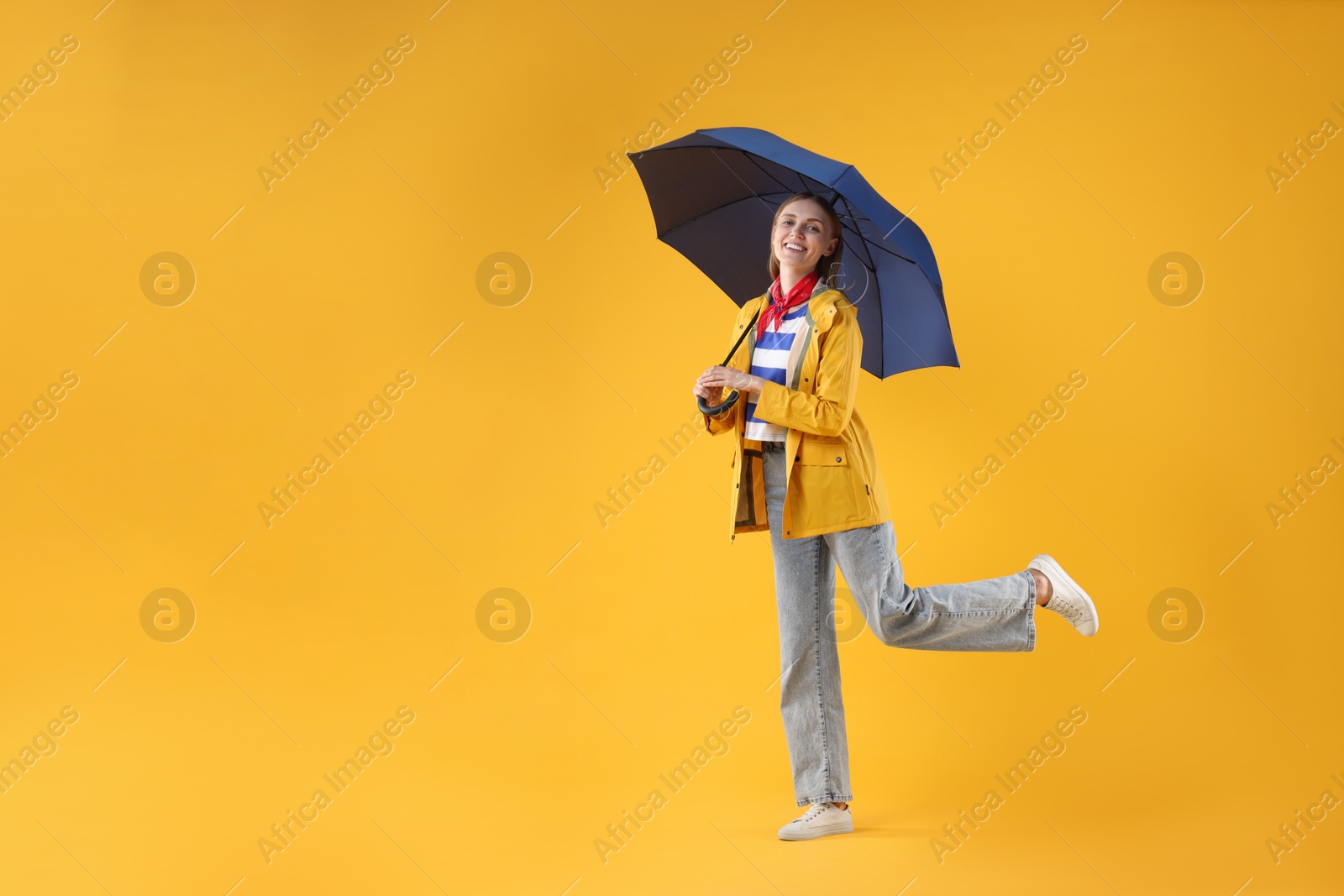 Photo of Woman with blue umbrella on yellow background, space for text