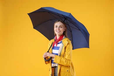 Woman with blue umbrella on yellow background