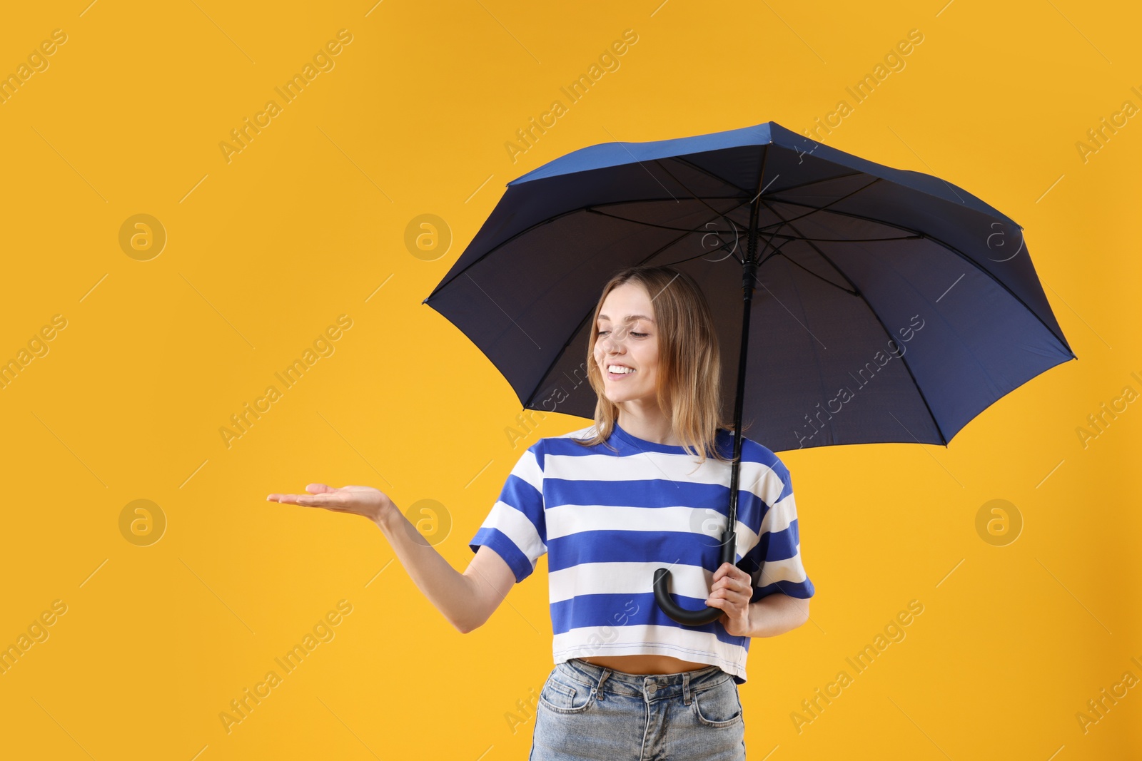 Photo of Woman with blue umbrella on yellow background