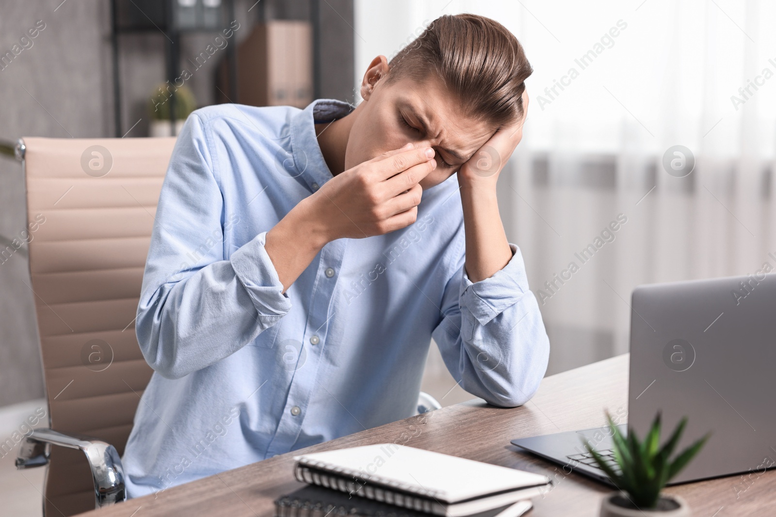 Photo of Young man suffering from sinusitis at wooden table indoors