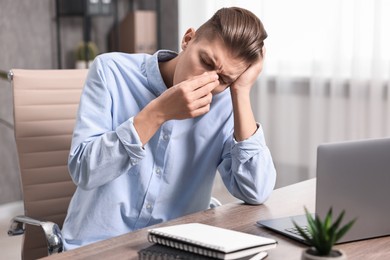 Young man suffering from sinusitis at wooden table indoors