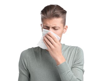 Young man with tissue suffering from sinusitis on white background