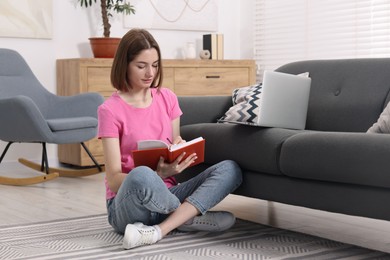 Photo of Teenager taking notes while working with laptop at home. Remote job