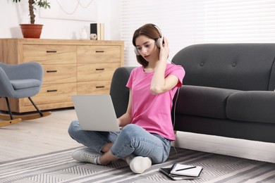 Teenager in headphones working with laptop at home. Remote job