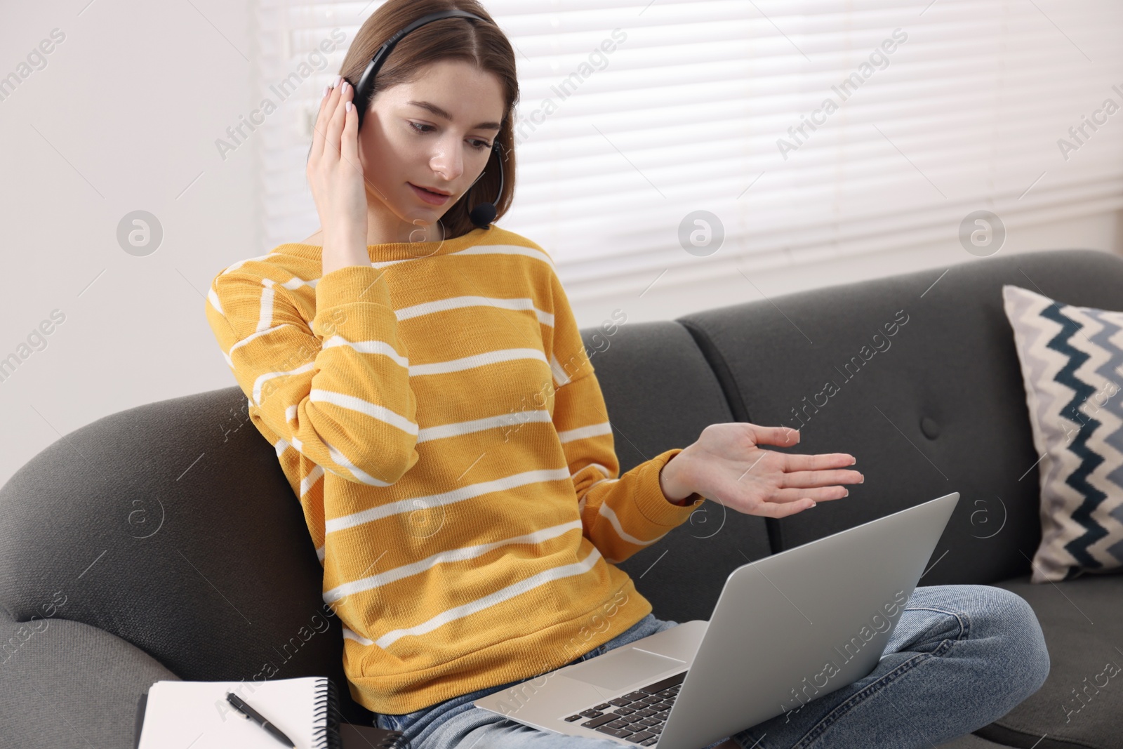 Photo of Teenager in headset having video chat via laptop at home. Remote work