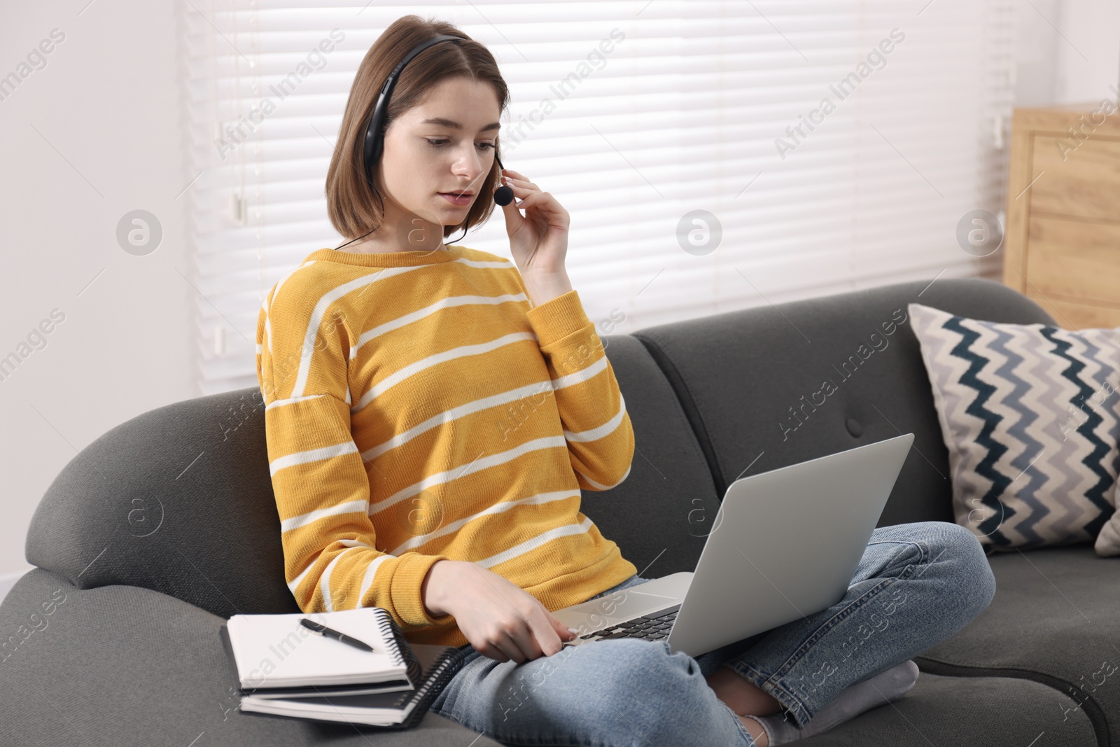 Photo of Teenager in headset having video chat via laptop at home. Remote work