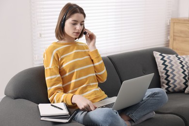 Teenager in headset having video chat via laptop at home. Remote work