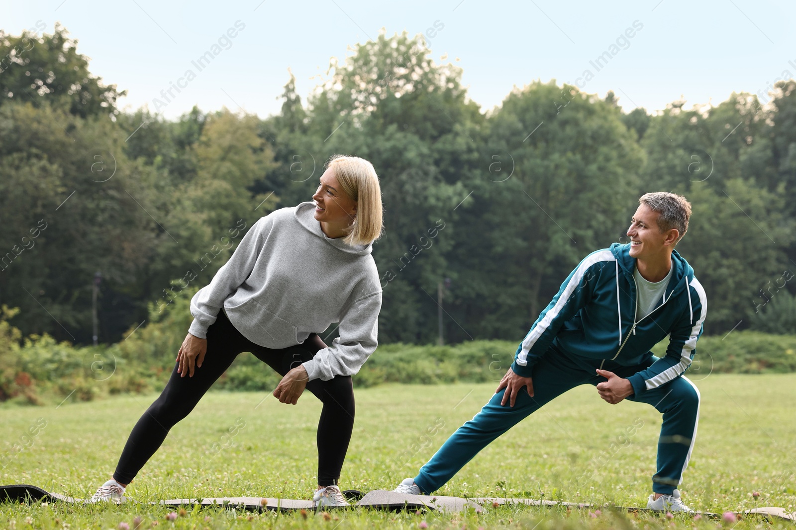 Photo of Happy couple doing exercises in park. Healthy lifestyle