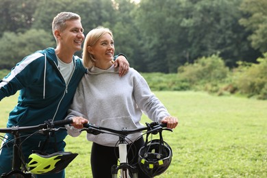 Photo of Happy couple with bicycles in park. Healthy lifestyle