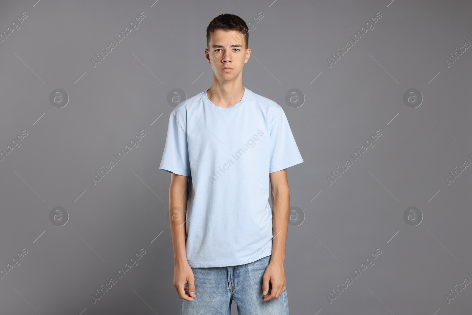 Photo of Teenage boy wearing light blue t-shirt on grey background