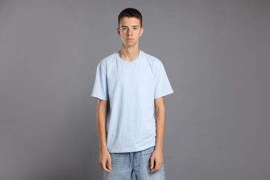 Photo of Teenage boy wearing light blue t-shirt on grey background