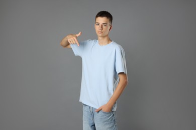 Teenage boy wearing light blue t-shirt on grey background