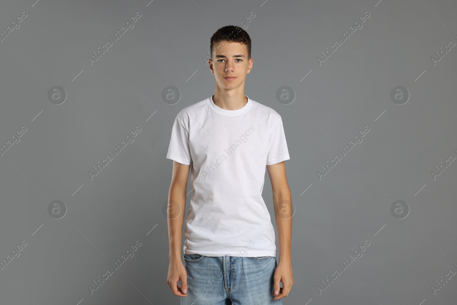 Photo of Teenage boy wearing white t-shirt on grey background