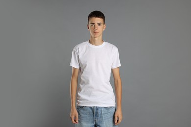 Teenage boy wearing white t-shirt on grey background