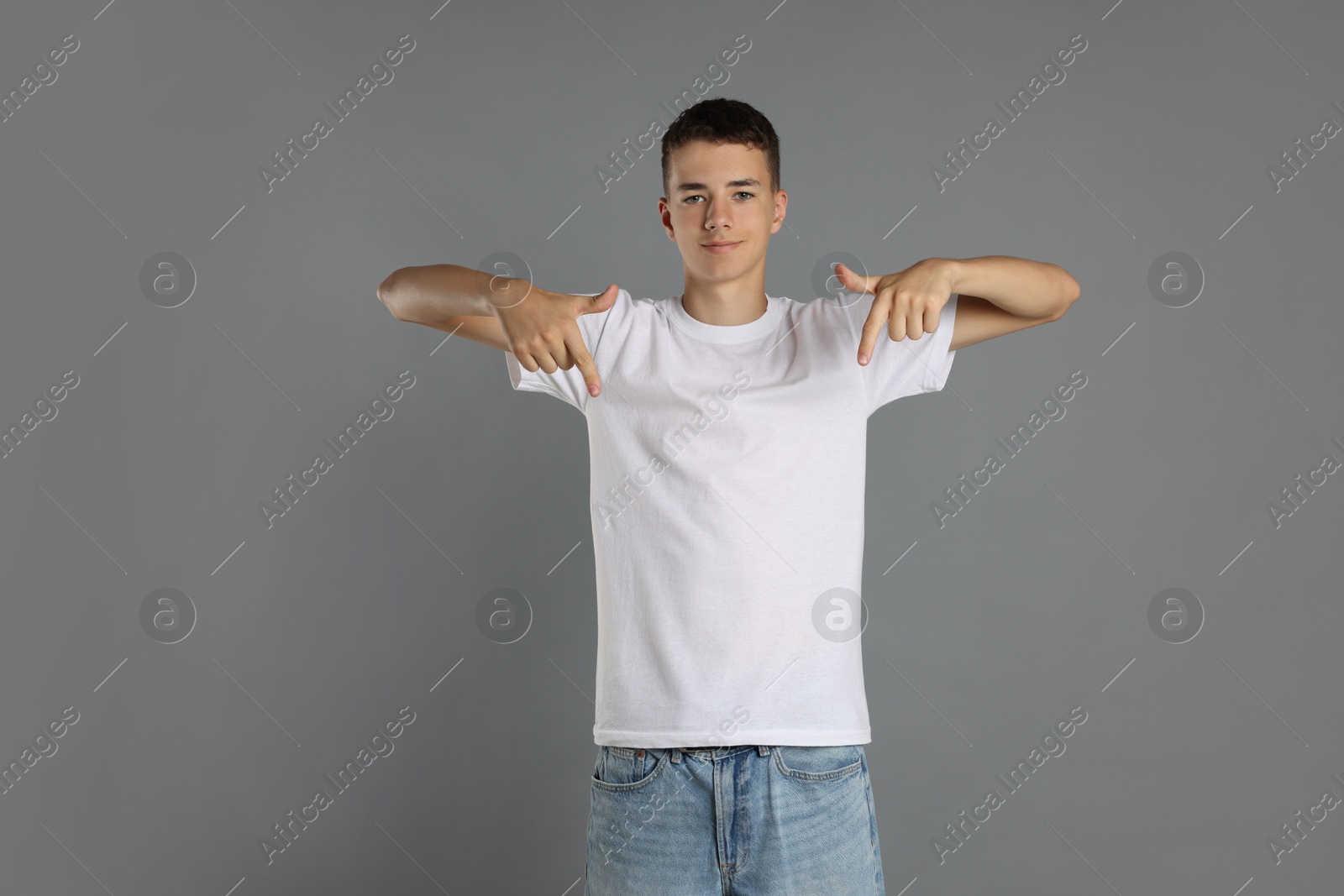 Photo of Teenage boy wearing white t-shirt on grey background