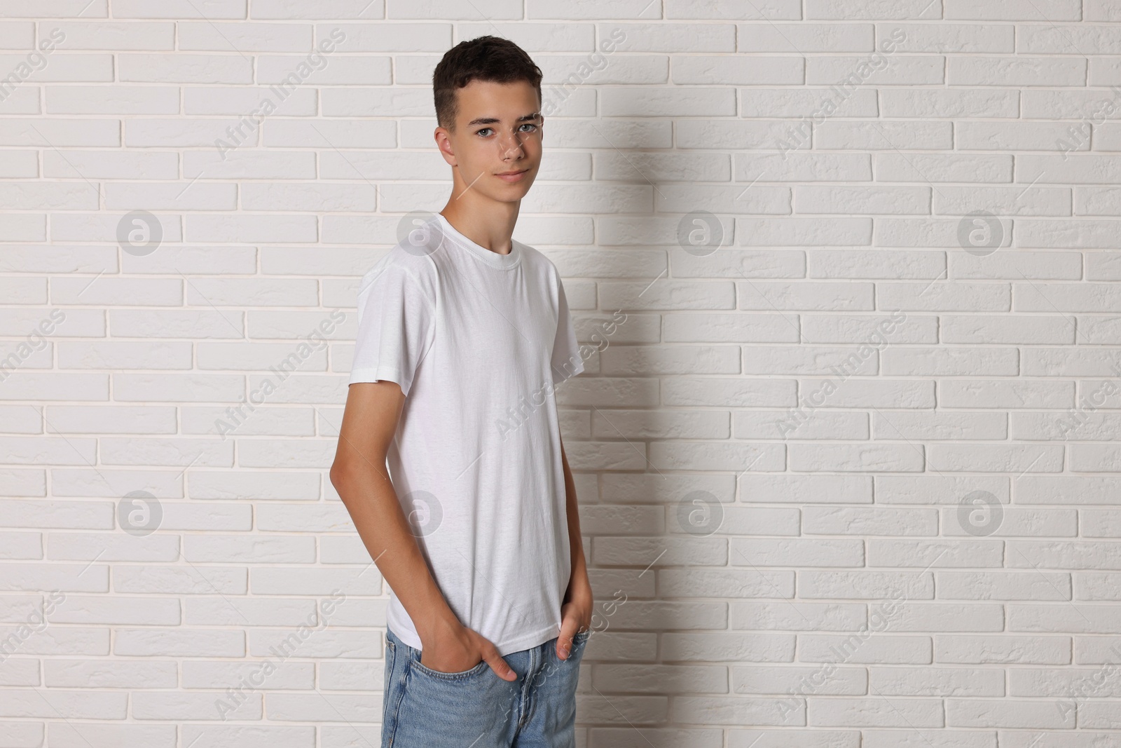 Photo of Teenage boy wearing t-shirt near white brick wall