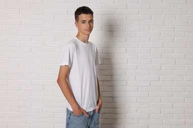 Teenage boy wearing t-shirt near white brick wall