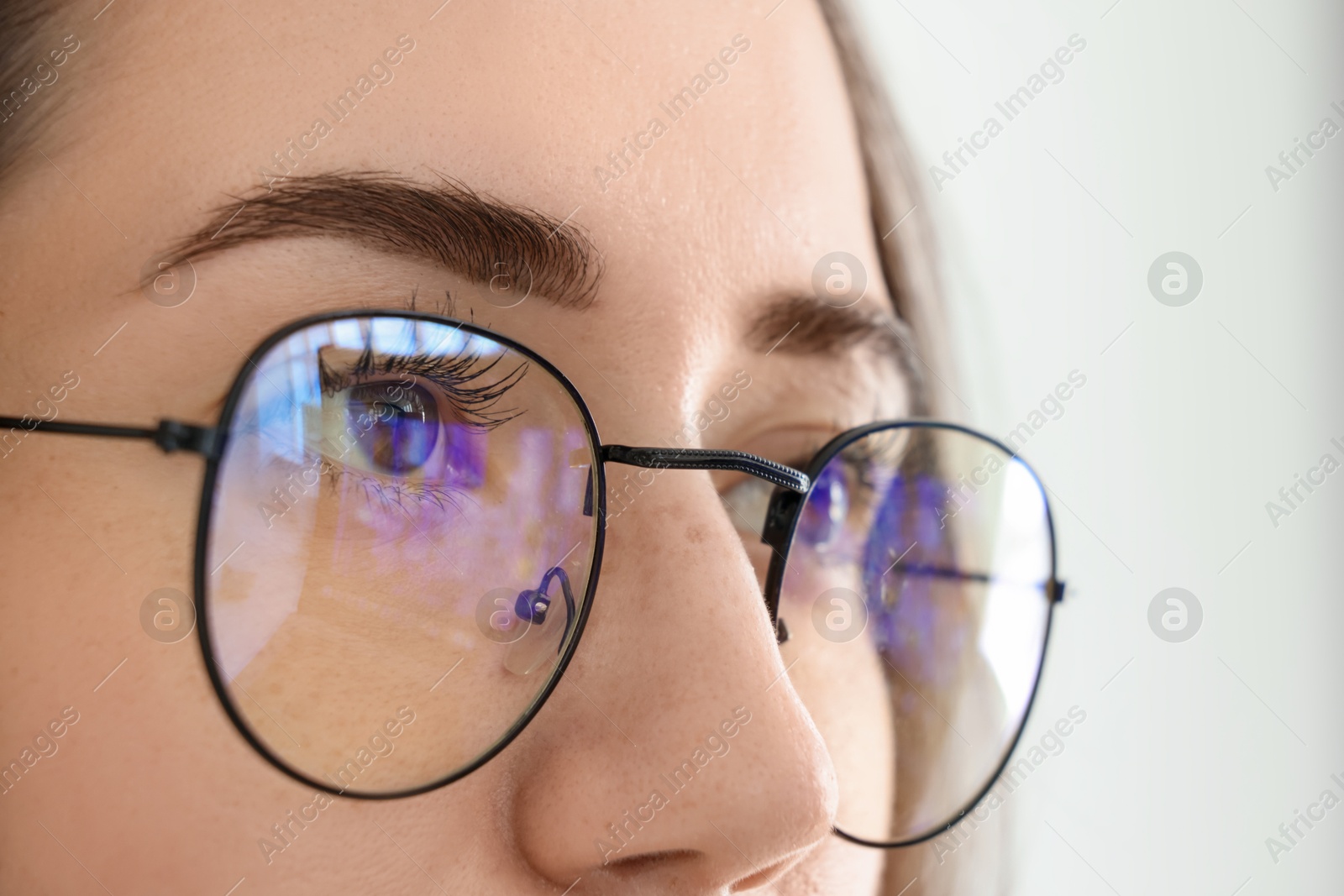 Photo of Closeup view of woman wearing eyeglasses on blurred background