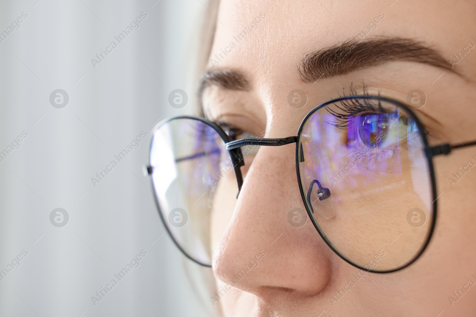 Photo of Closeup view of woman wearing eyeglasses on blurred background