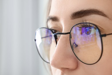 Closeup view of woman wearing eyeglasses on blurred background