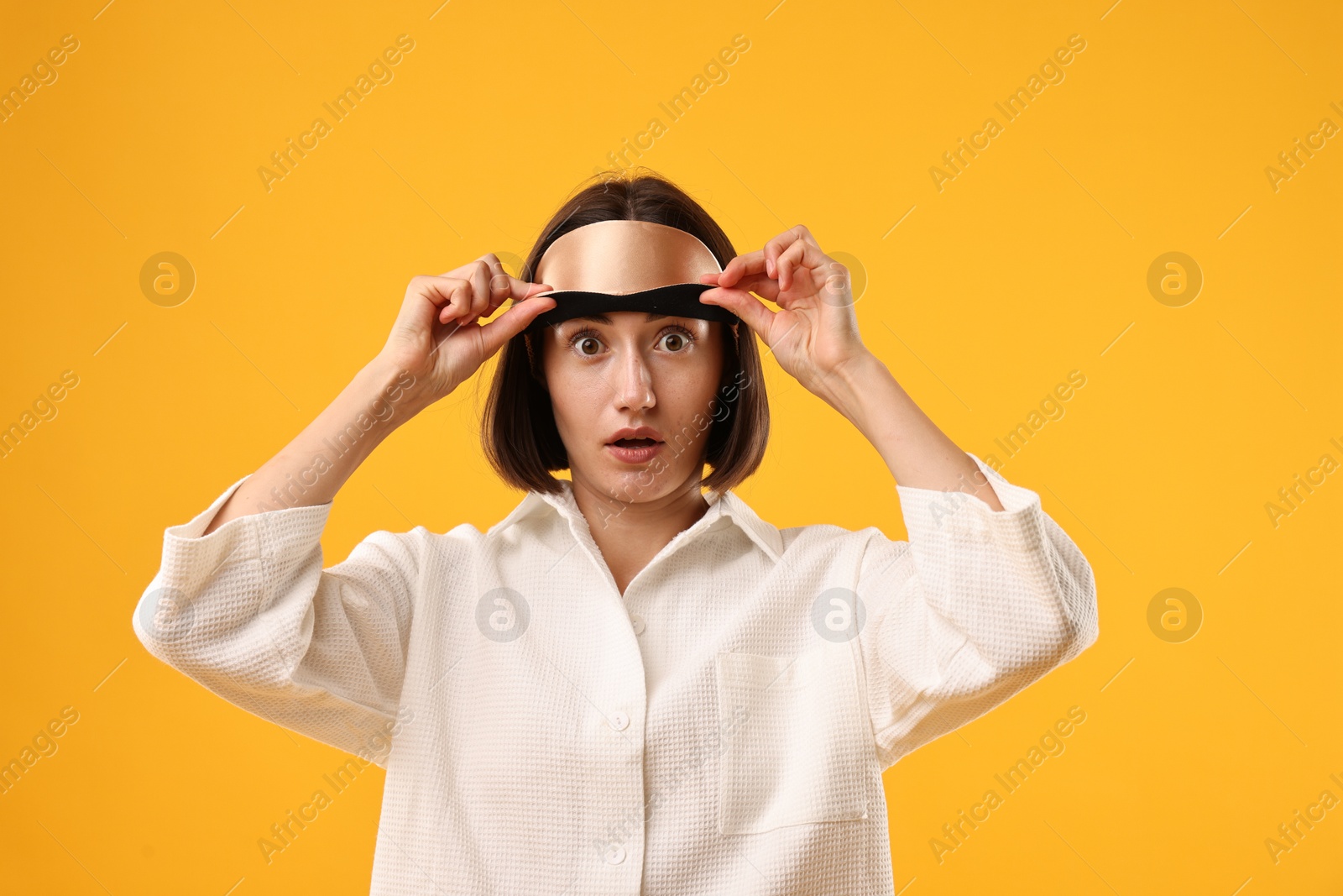 Photo of Overslept young woman with sleep mask on yellow background