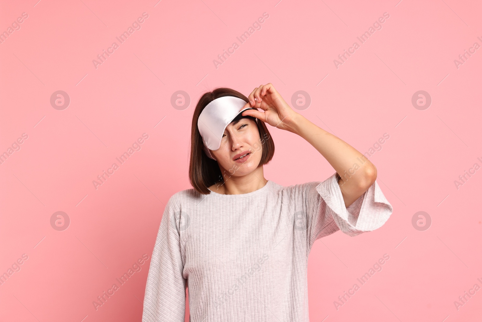 Photo of Overslept young woman with sleep mask on pink background