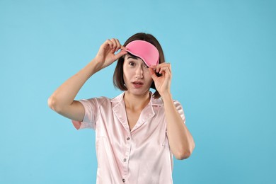 Photo of Overslept young woman with sleep mask on light blue background