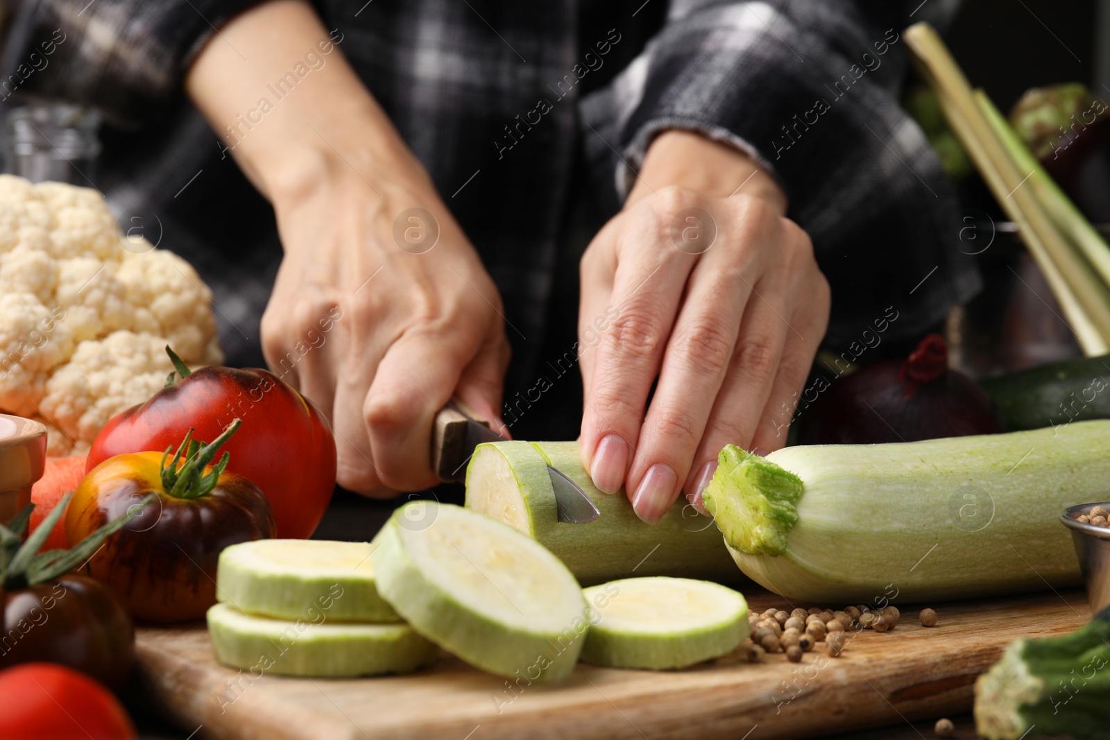 Photo of Cooking vegetable stew. Woman cutting zucchini at table, closeup