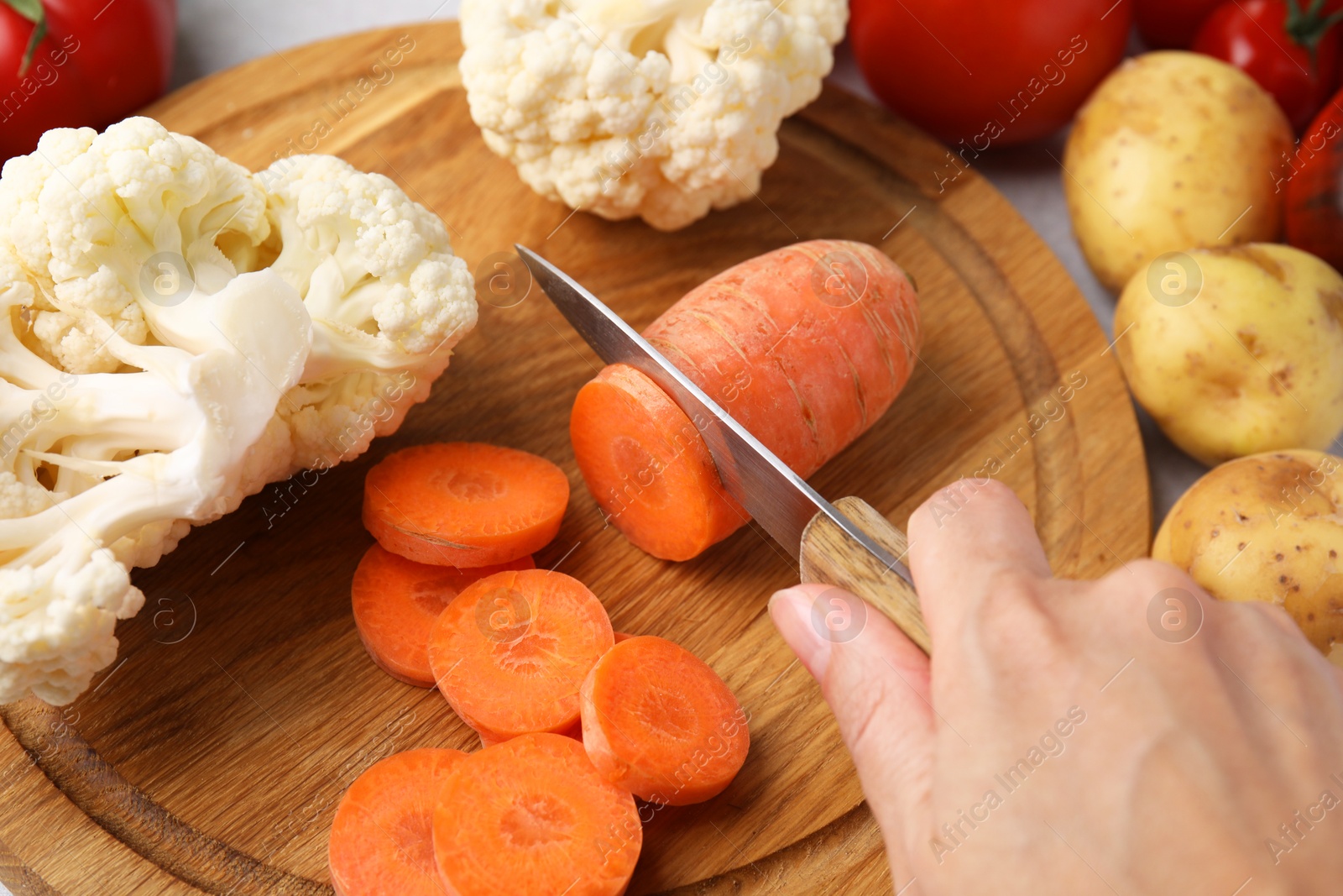 Photo of Cooking vegetable stew. Woman cutting carrot at table, closeup