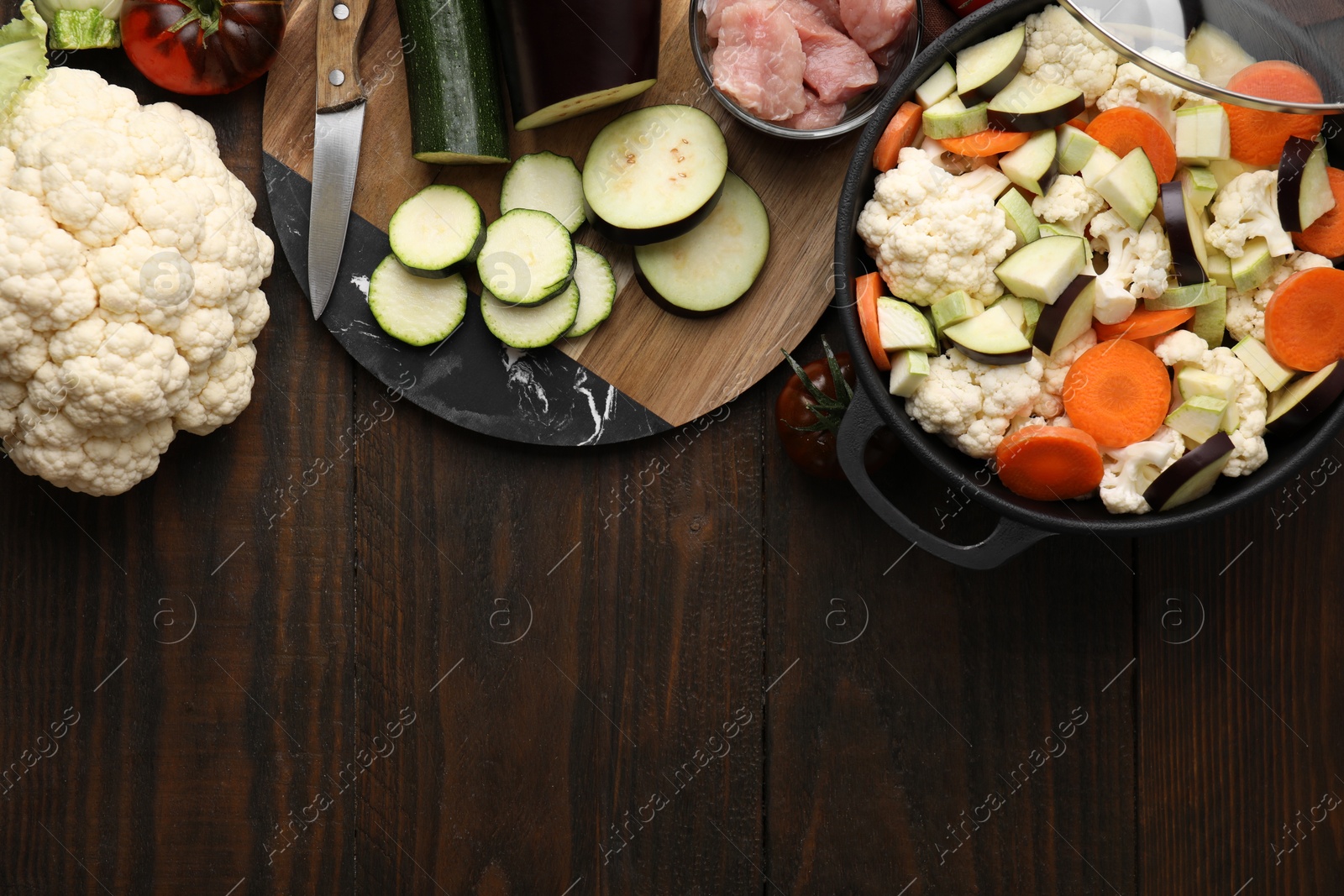 Photo of Cooking stew. Cut raw vegetables in pot on wooden table