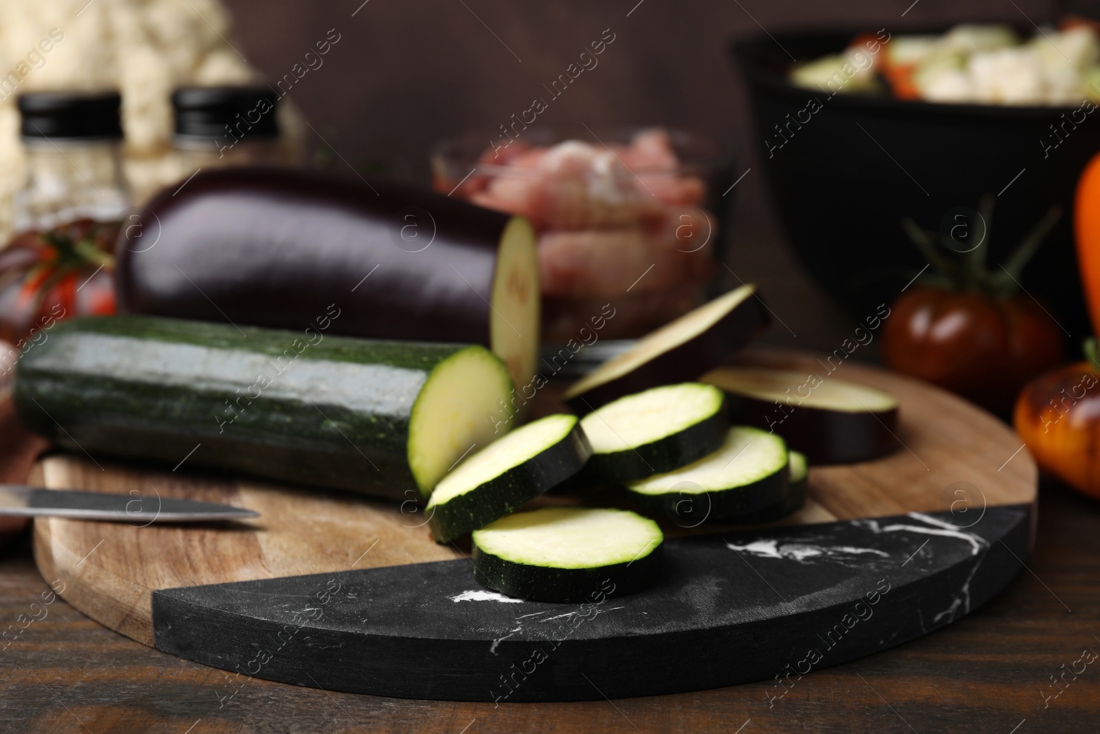 Photo of Cooking stew. Cut zucchini and eggplant on wooden table, closeup