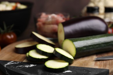 Photo of Cooking stew. Cut zucchini and eggplant on wooden table, closeup