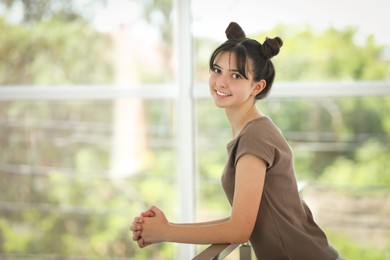 Portrait of smiling teenage girl indoors. Space for text