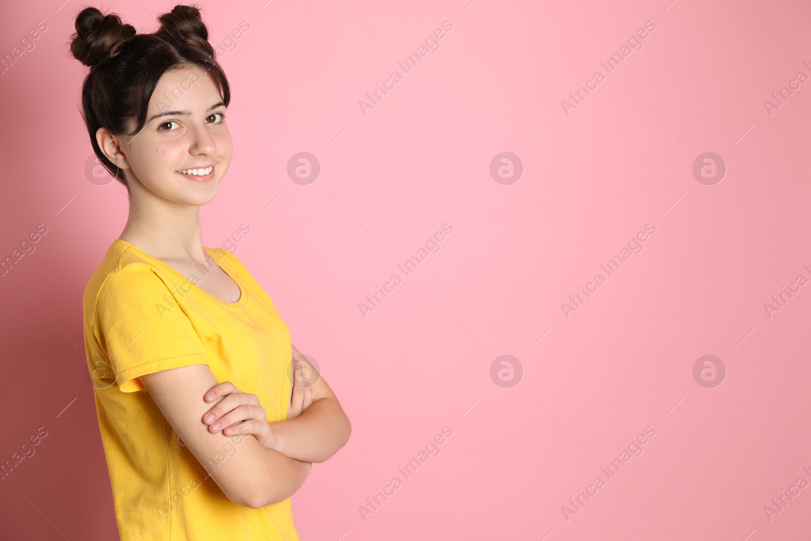 Photo of Portrait of smiling teenage girl on pink background. Space for text