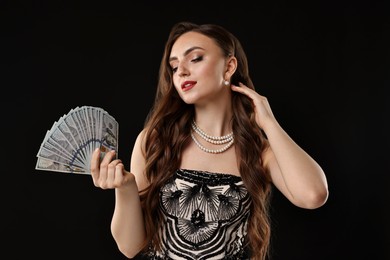 Charming woman with dollar banknotes on black background