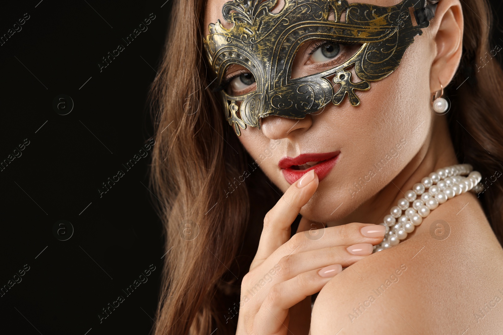 Photo of Beautiful woman wearing carnival mask on black background, closeup