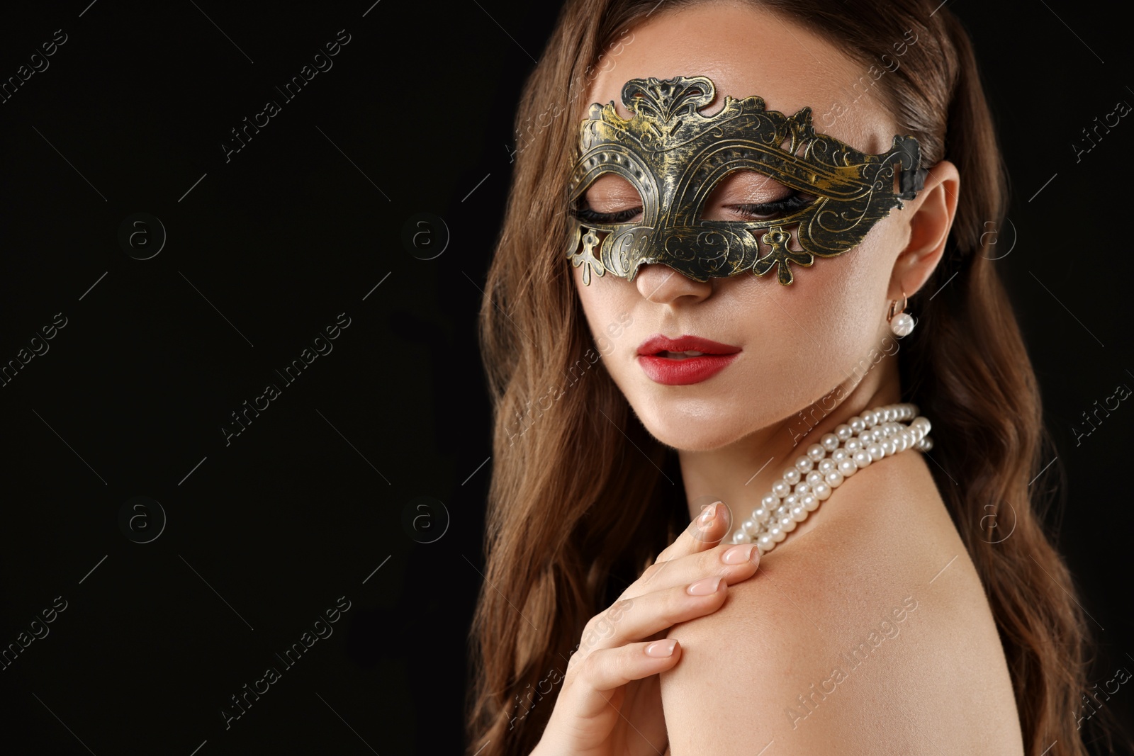 Photo of Beautiful woman wearing carnival mask on black background, closeup. Space for text