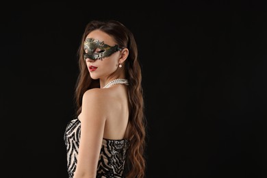 Photo of Beautiful woman wearing carnival mask on black background. Space for text