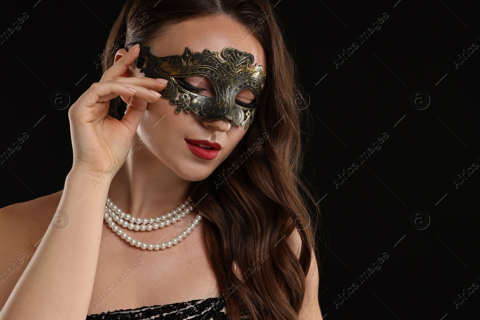 Photo of Beautiful woman wearing carnival mask on black background, closeup. Space for text