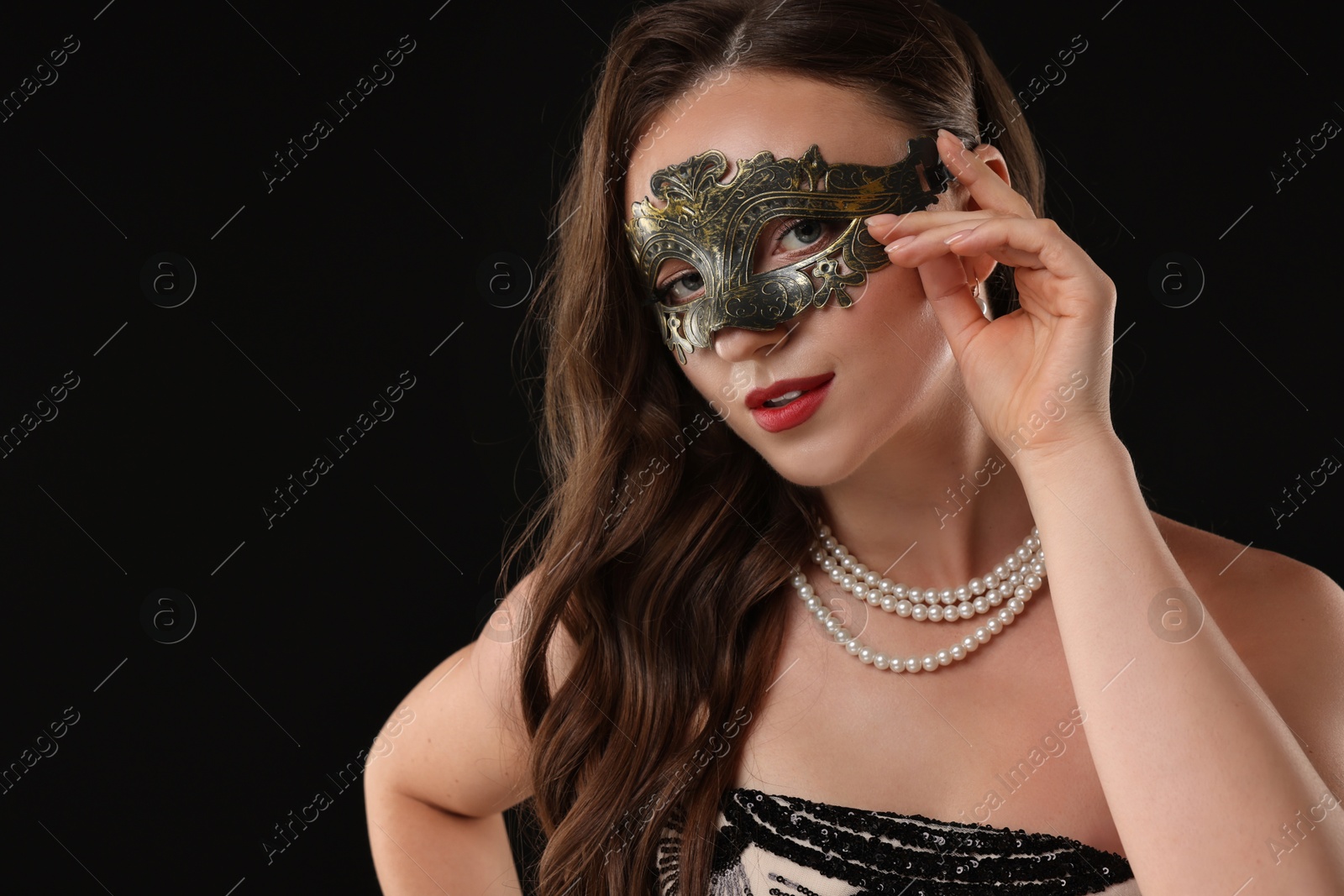 Photo of Beautiful woman wearing carnival mask on black background, closeup. Space for text