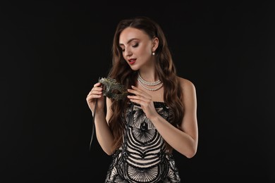 Photo of Beautiful woman with carnival mask on black background