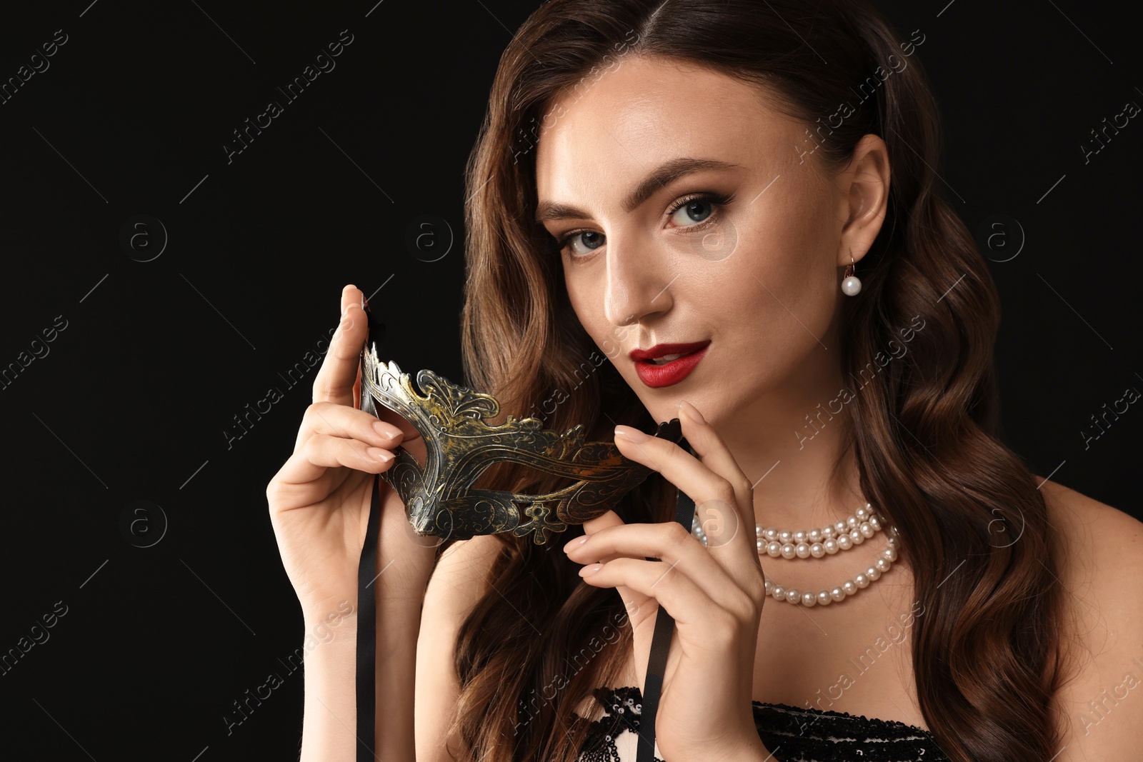 Photo of Beautiful woman with carnival mask on black background