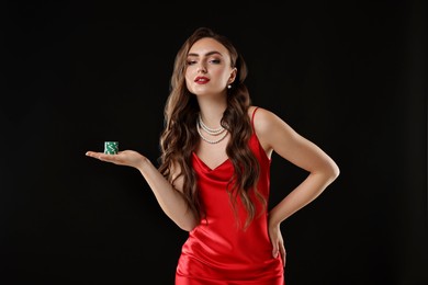 Charming woman with poker chips on black background