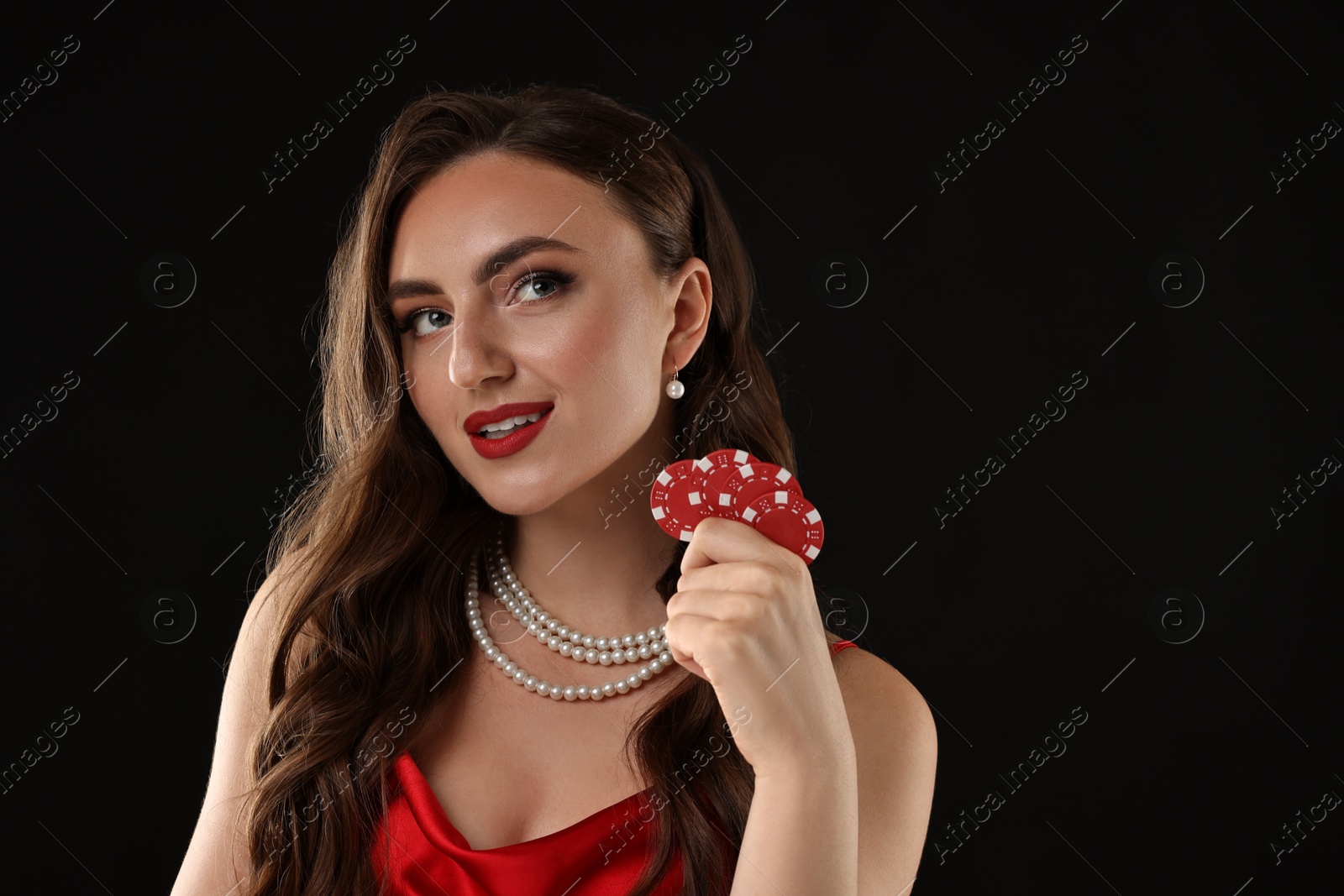 Photo of Charming woman with poker chips on black background. Space for text