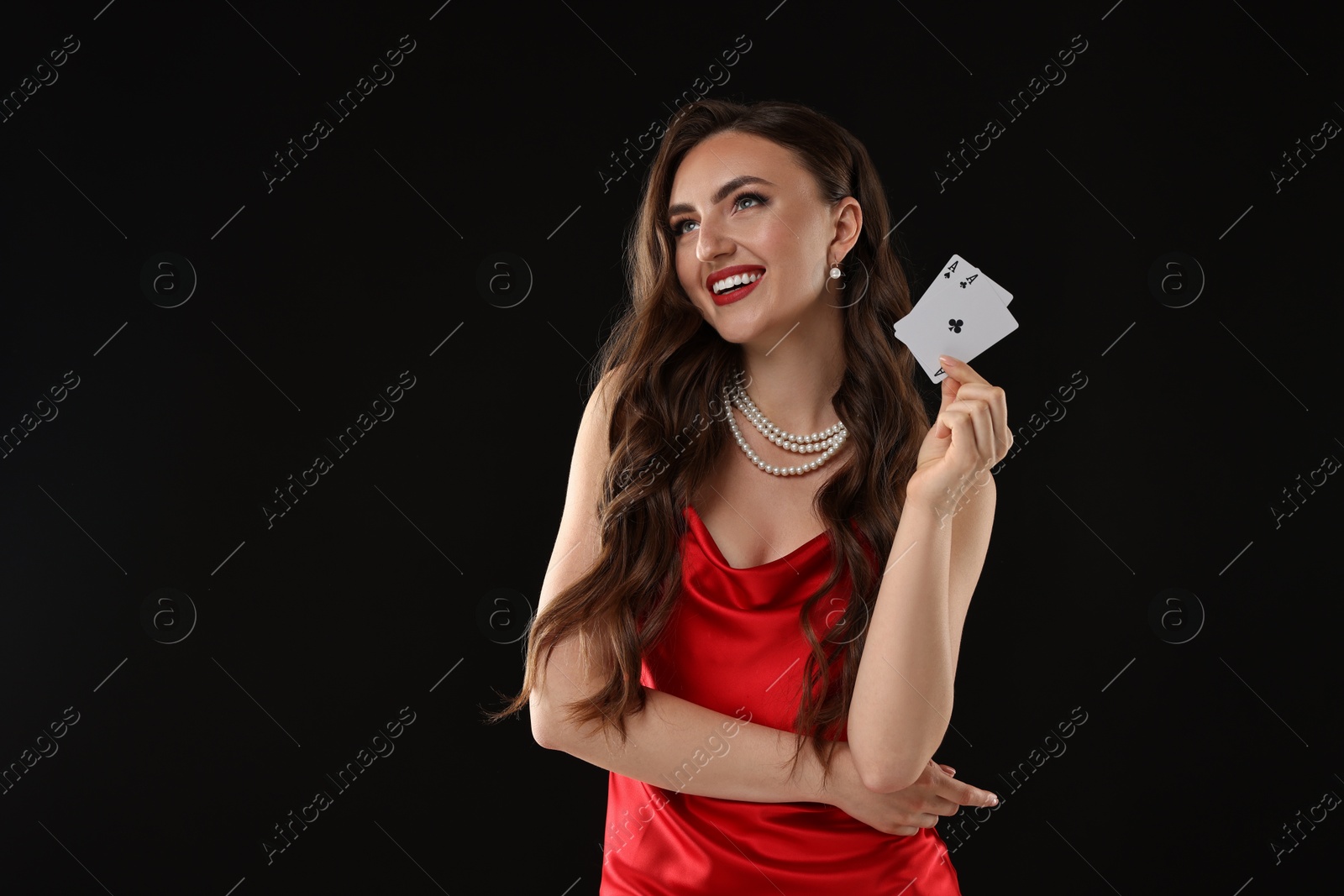 Photo of Poker game. Smiling woman with playing cards on black background. Space for text