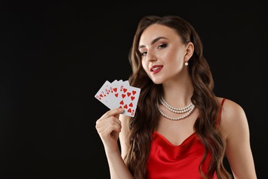 Photo of Poker game. Charming woman with playing cards on black background. Space for text