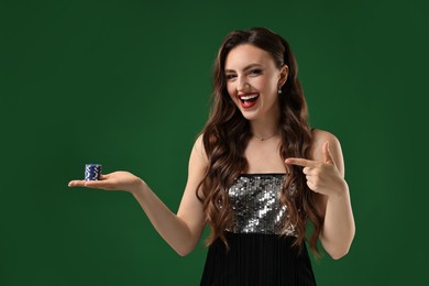 Happy woman pointing at poker chips on green background