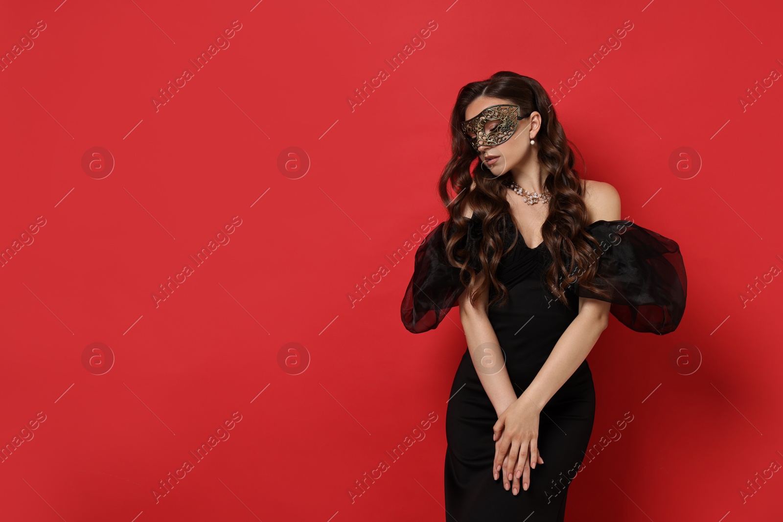 Photo of Beautiful woman wearing carnival mask on red background. Space for text